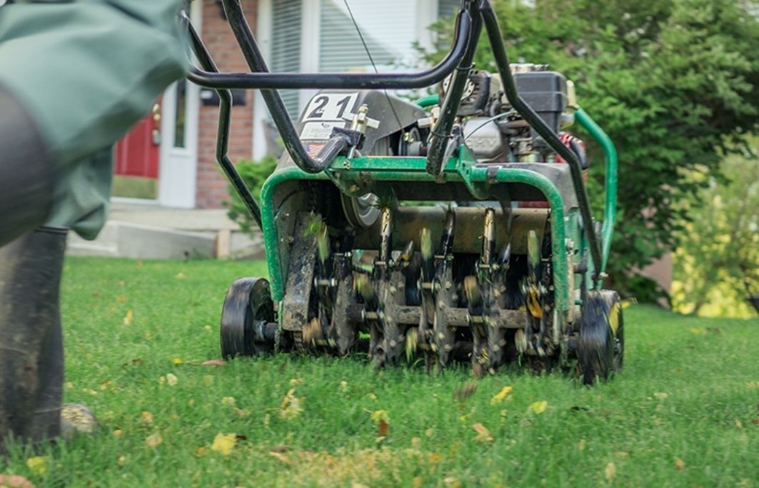 man pushing airation machine over lawn